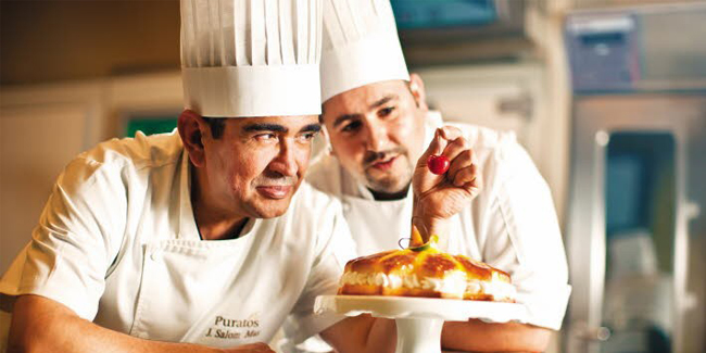 Two chefs finishing an artisan cake